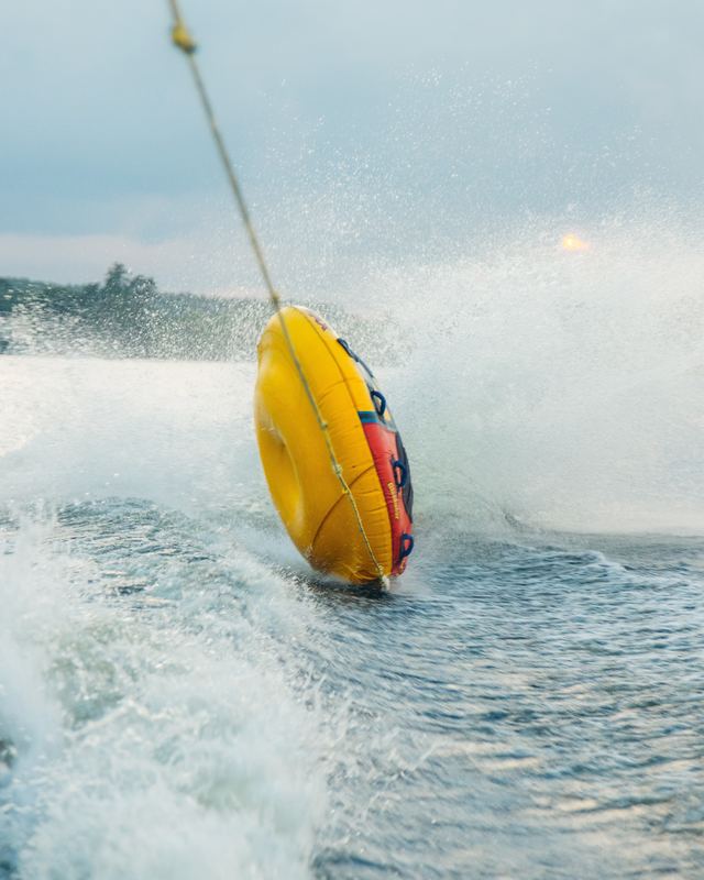 A tube skimming the lake behind a boat, spray flying