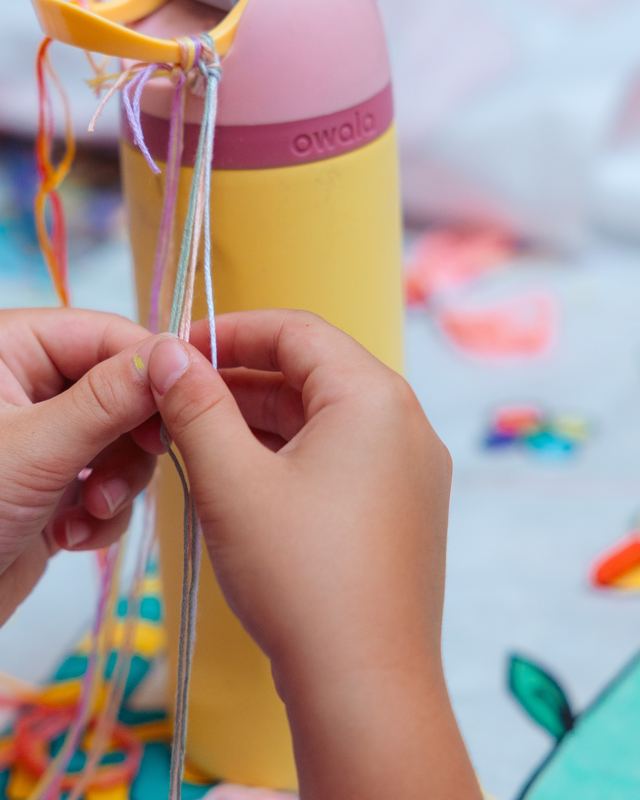 Hands tying a friendship bracelet