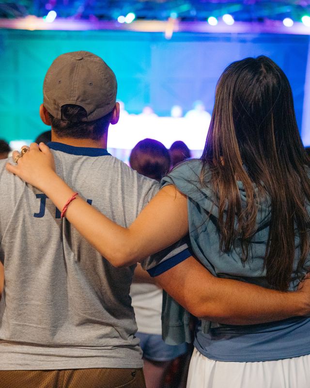 Two campers from behind, arms around each other at an evening show